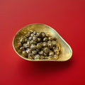 Gold and brown coloured hard boiled whisky and Ginger flavoured sweets in a gold bowl with a red background 