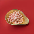 100g of red and white striped Berwick Cockles peppermint flavoured soft mints in a gold bowl with a red background 