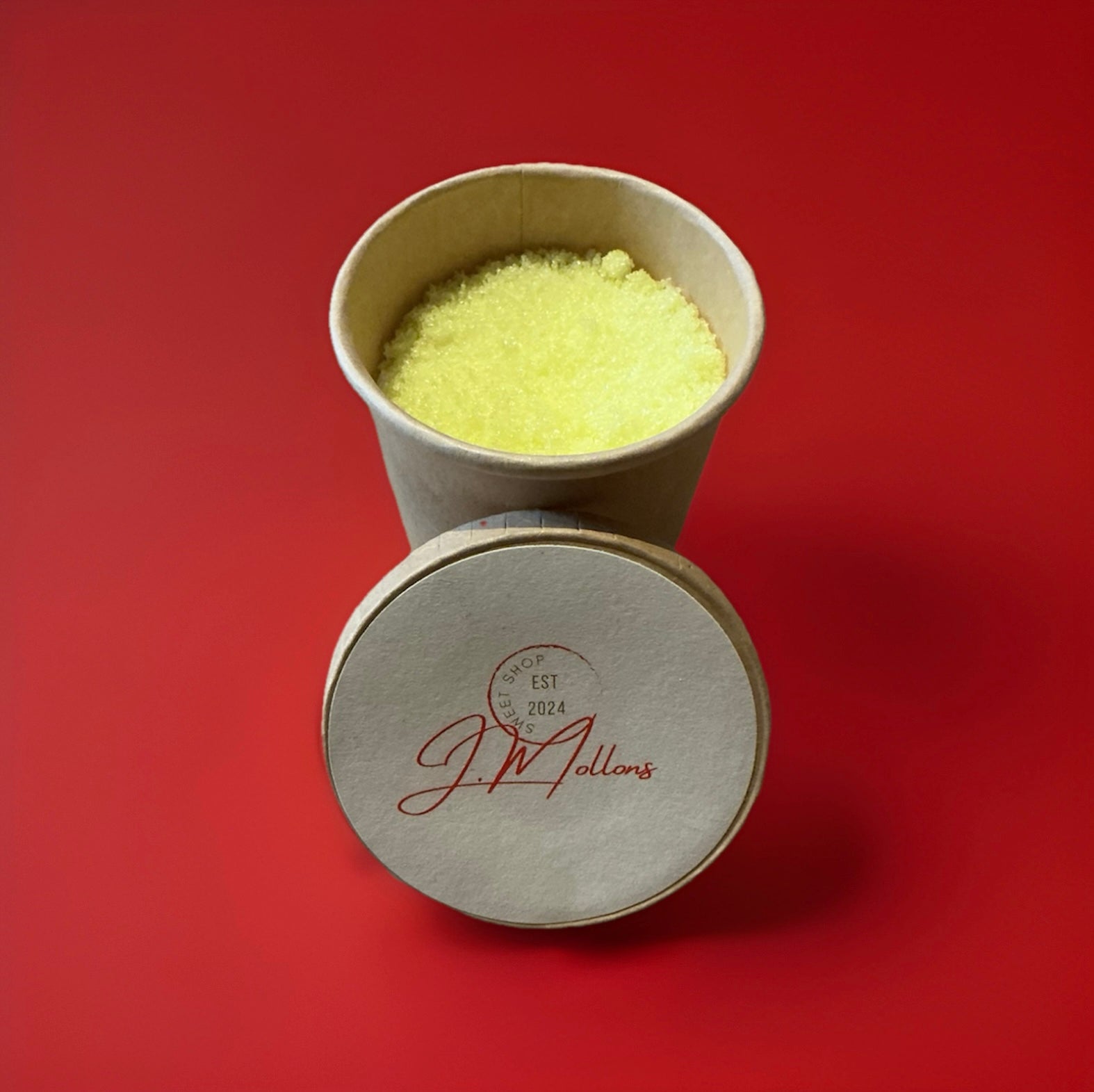 Yellow lemon flavoured sherbet in a brown paper pot on a red background 