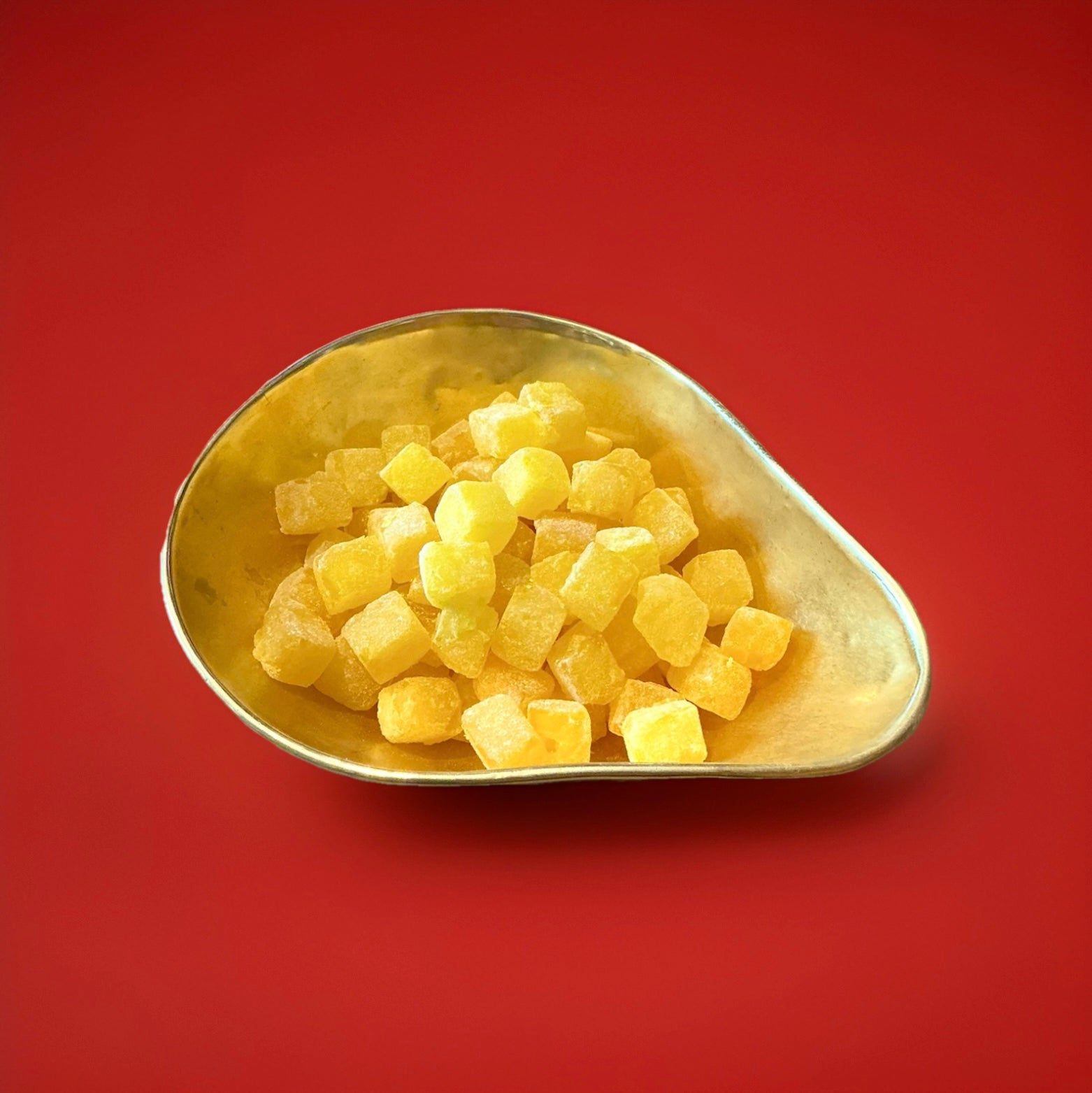 Hard boiled yellow pineapple cubes in a gold bowl on a red background 