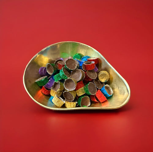 Chocolate fondant in multicoloured foil cups in a gold bowl on a red background 