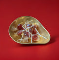 Hard boiled dark red cherry lolly in a gold bowl on a red background 