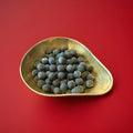 Round shaped black coloured liquorice toffee Bon Bon’s in a gold bowl on a red background 