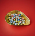 Individually foil wrapped chocolate footballs in a gold bowl on a red background 