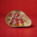 Individually wrapped hard boiled red yellow and green lolly in a gold bowl on a red background 