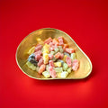 Multicoloured Barrett jelly babies in a gold bowl on a red background 