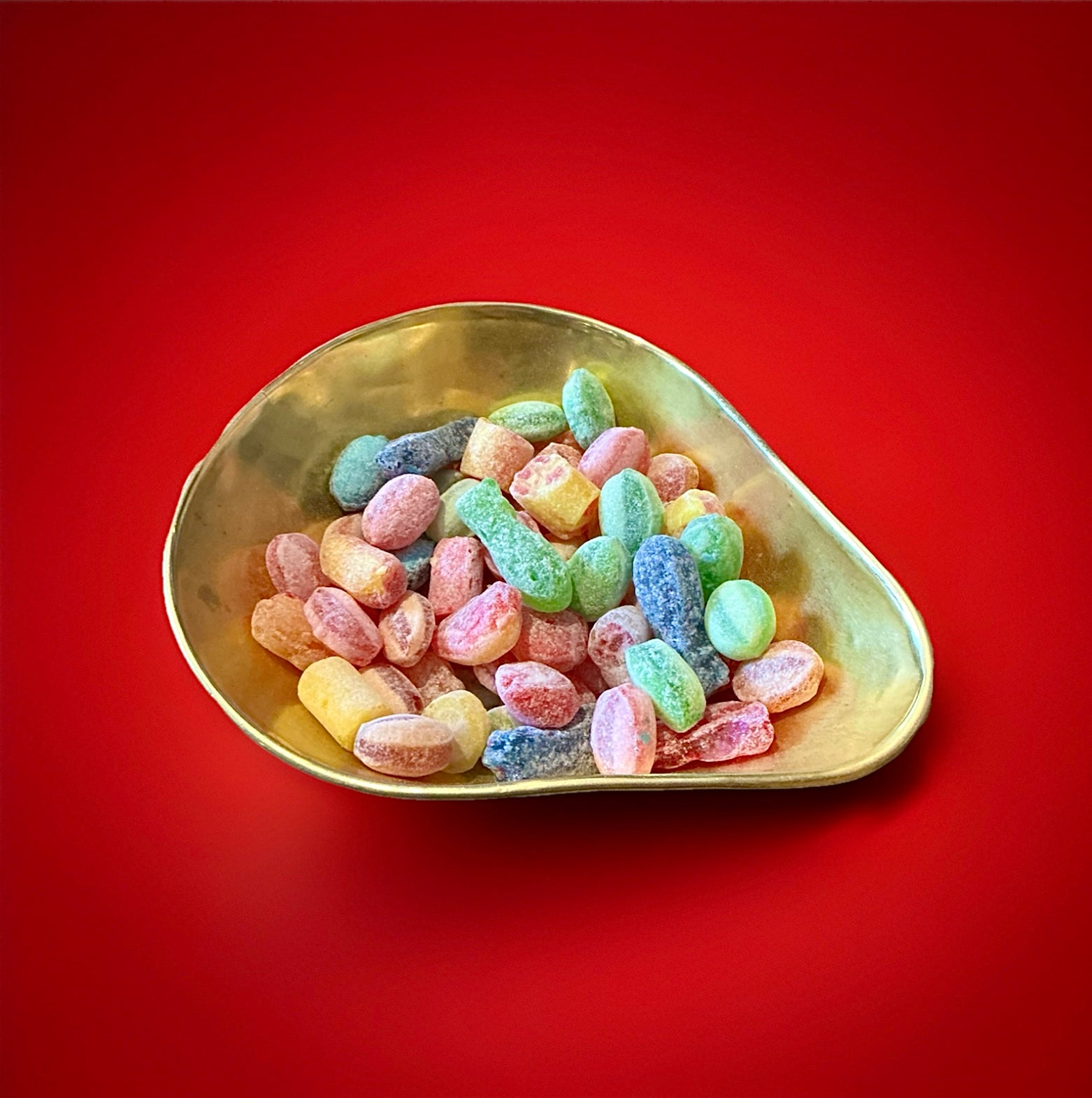 Yorkshire Mix hard boiled mixed fruit flavoured sweets with a sugar coating in a gold bowl with a red background 