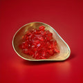 Fruity lip shaped red jelly sweets in a gold bowl on a red background 
