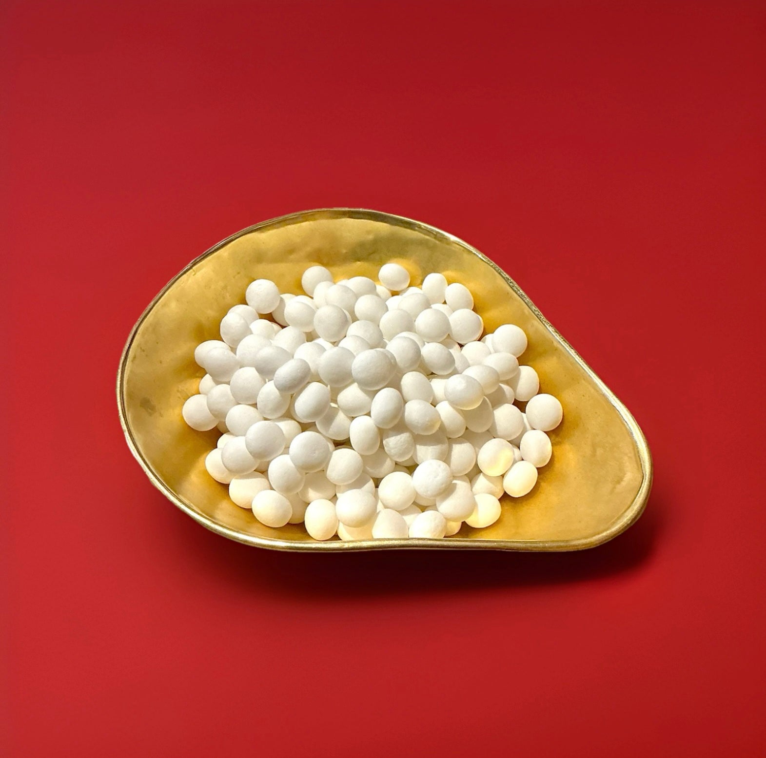 White mint imperial sweets in a gold bowl on a red background 