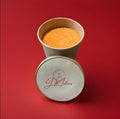 Orange coloured and flavoured sherbet in a brown paper pot on a red background 