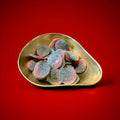 Large disc shaped fizzy raspberry and liquorice sunsets in a gold bowl with a red background 