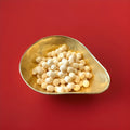 Round shaped yellow coloured lemon flavoured Bon Bon’s in a gold bowl on a red background 