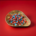 White red and blue round hard boiled d hard boiled sweets with a bubblegum flavour and a fizzy sherbet centre in a gold bowl with a red background 