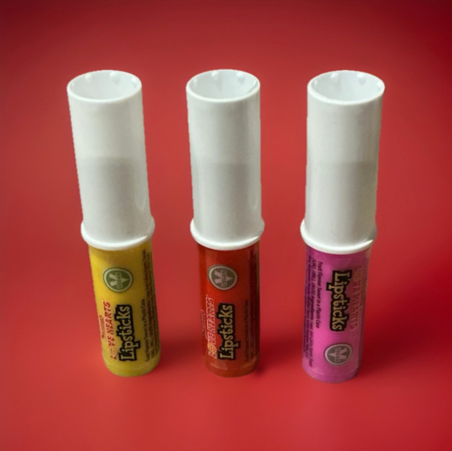 A compressed stick of chalky love heart flavoured sherbet with a white lid on a red background 