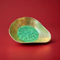 Green coloured watermelon flavoured millions in a gold bowl on a red background 