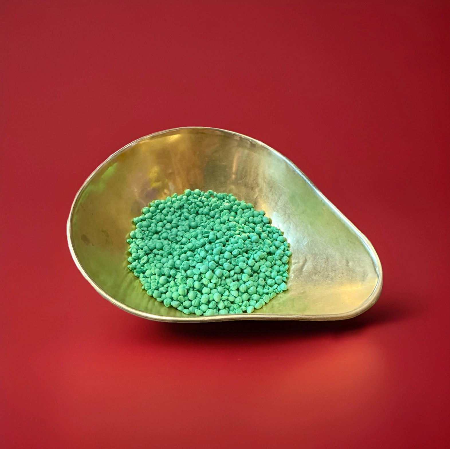 Green coloured watermelon flavoured millions in a gold bowl on a red background 