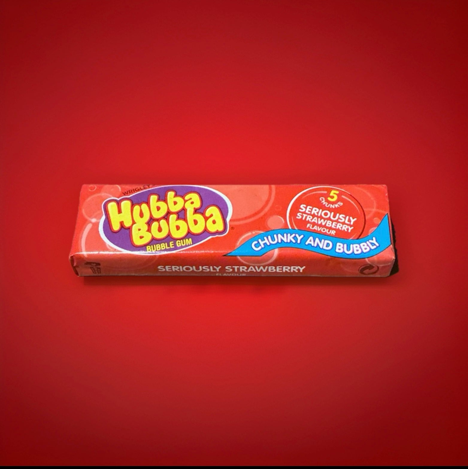 Strawberry flavoured Hubba bubba bubblegum squares in a red wrapper on a red background 