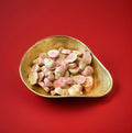 White and strawberry flavoured chocolate in the shape of skulls in a gold bowl on a red background 