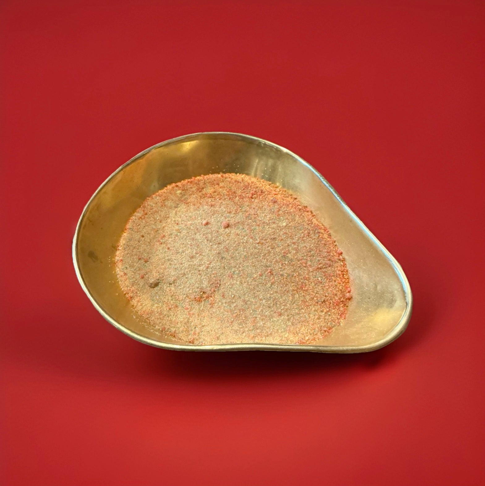 Multicoloured rainbow crystals sherbet in a gold bowl on a red background 