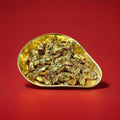 Individually wrapped hard boiled butterscotch sweets in gold wrappers in a gold bowl with a red background 