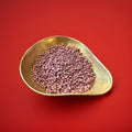 Purple coloured blackcurrant flavoured millions in a gold bowl on a red background 