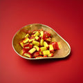 Red and yellow passion fruit flavoured sweets in a gold bowl with a red background 