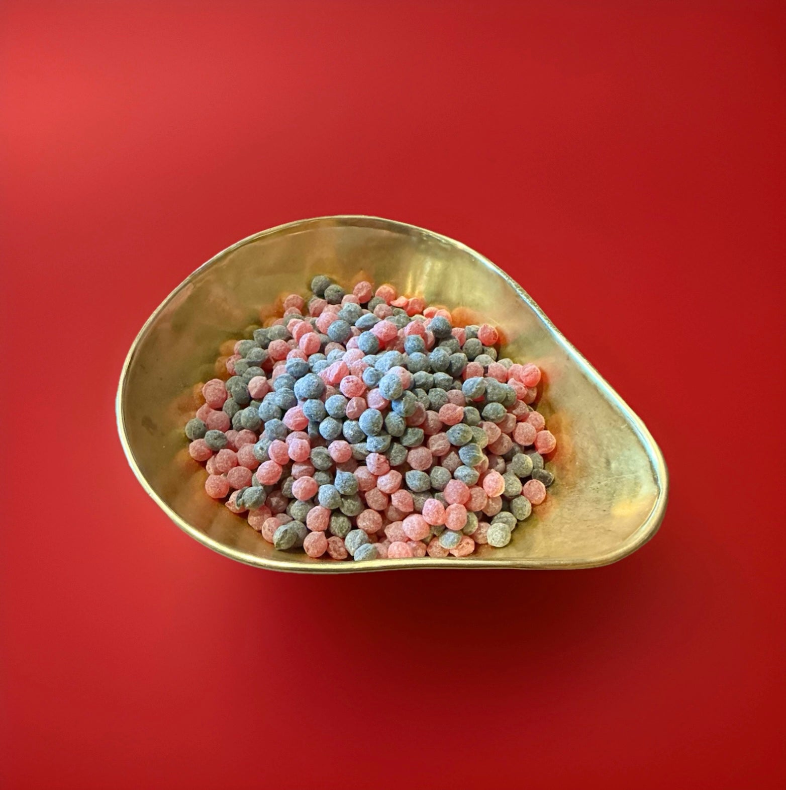 Hard boiled BlackBerry and Raspberry flavoured pips in a gold bowl on a red background 