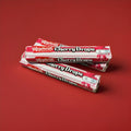 Hard boiled cherry flavoured sweets in a red pink and white wrapper on a red background 