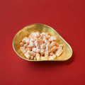 Orange iron brew flavoured jelly sweets in the traditional jelly baby shape in a gold bowl with a red background 