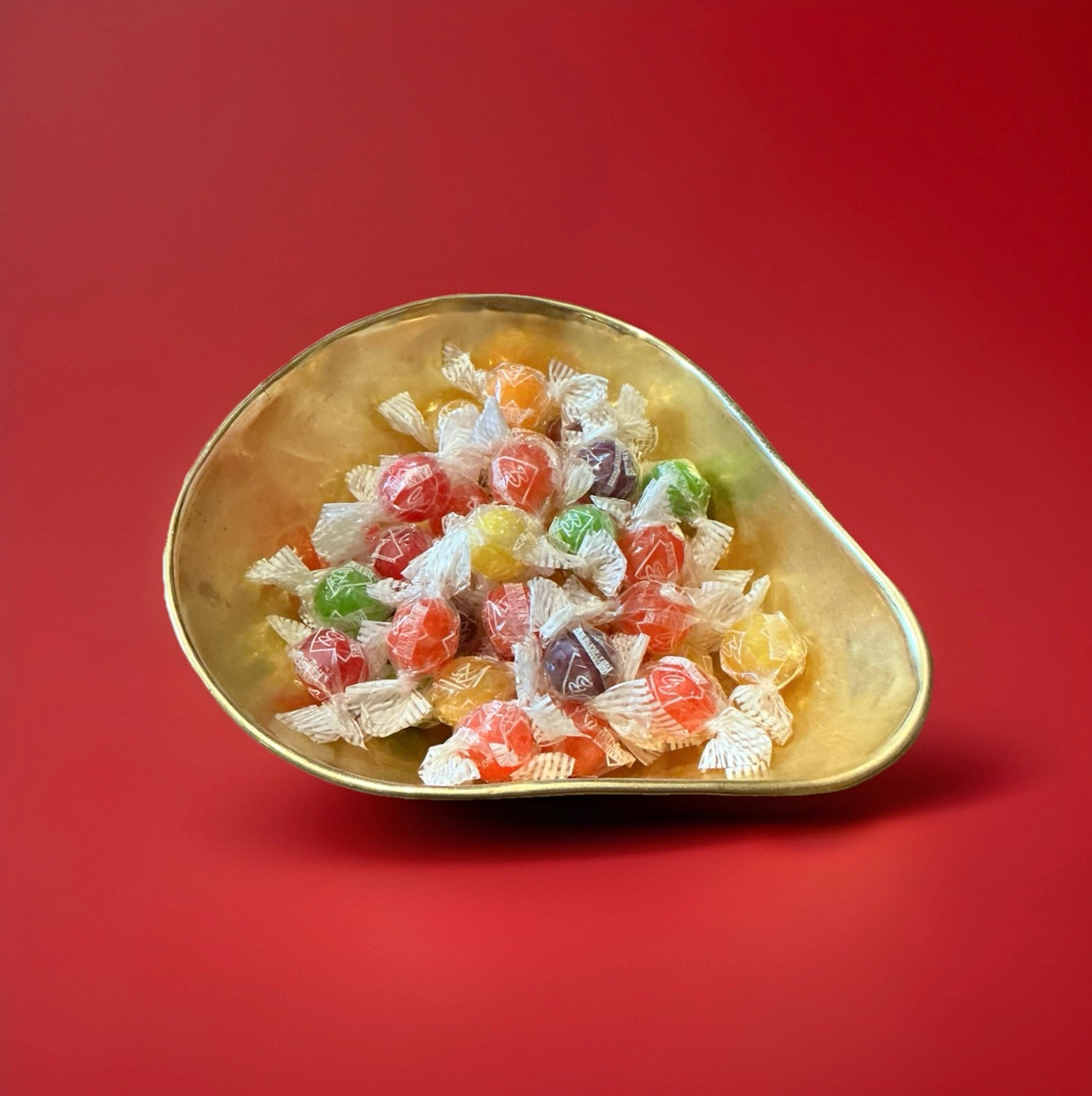 Barnetts Sherbons are round hard boiled fruit flavoured sweets with a fizzy sherbet centre in a gold bowl with a red background 