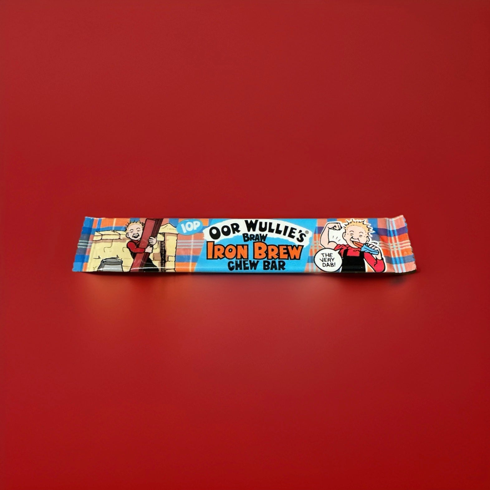 Oor wullie’s iron brew flavoured chew bar in a blue and tartan wrapper on a red background 