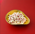 Pink and white coloured strawberry milkshake flavoured bottles in a gold bowl on a red background 