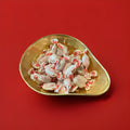 Individually wrapped Mintoes butter mints in a gold bowl on a red background 