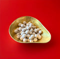 Light brown round Bristows salted caramel Bon Bon’s in a gold bowl with a red background 