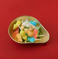 Multicoloured sugar mice lollies in a gold bowl with a red background 