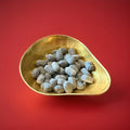 Hard boiled oval shaped Army and Navy sweets in a gold bowl on a red background 