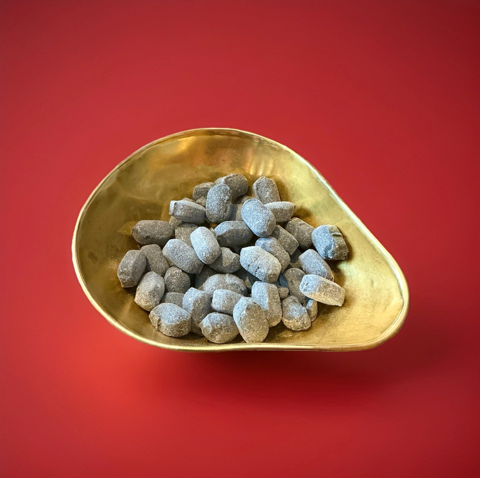 Hard boiled oval shaped Army and Navy sweets in a gold bowl on a red background 