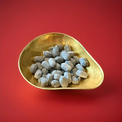 Hard boiled oval shaped Army and Navy sweets in a gold bowl on a red background 