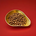 Milk chocolate covered peanuts in a gold bowl on a red background 