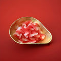Fang shaped red and white coloured gummy jelly sweets with a fruit flavour in a gold bowl on a red background 