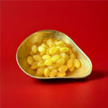 Yellow lemon flavoured and shaped hard boiled sweets with a sherbet centre in a gold bowl with a red background 