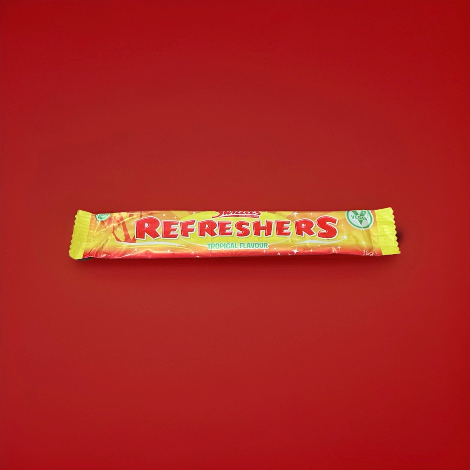 Wrapped yellow tropical flavoured chew bar on a red background 