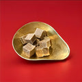 Large pieces of salted caramel fudge in a gold bowl with a red background 
