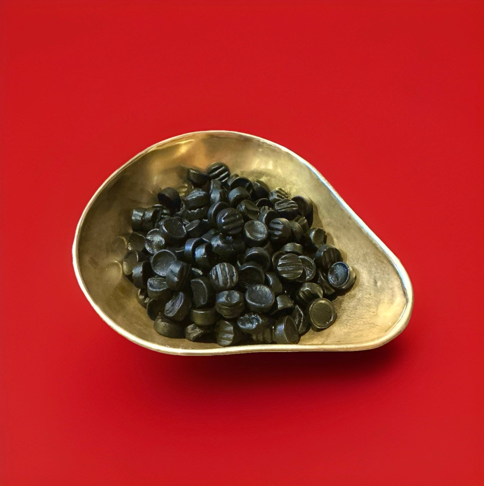 Poor bens liquorice and aniseed round gummy sweets in a gold bowl with a red background 