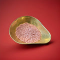 Pink colour strawberry flavoured millions in a gold bowl on a red background 