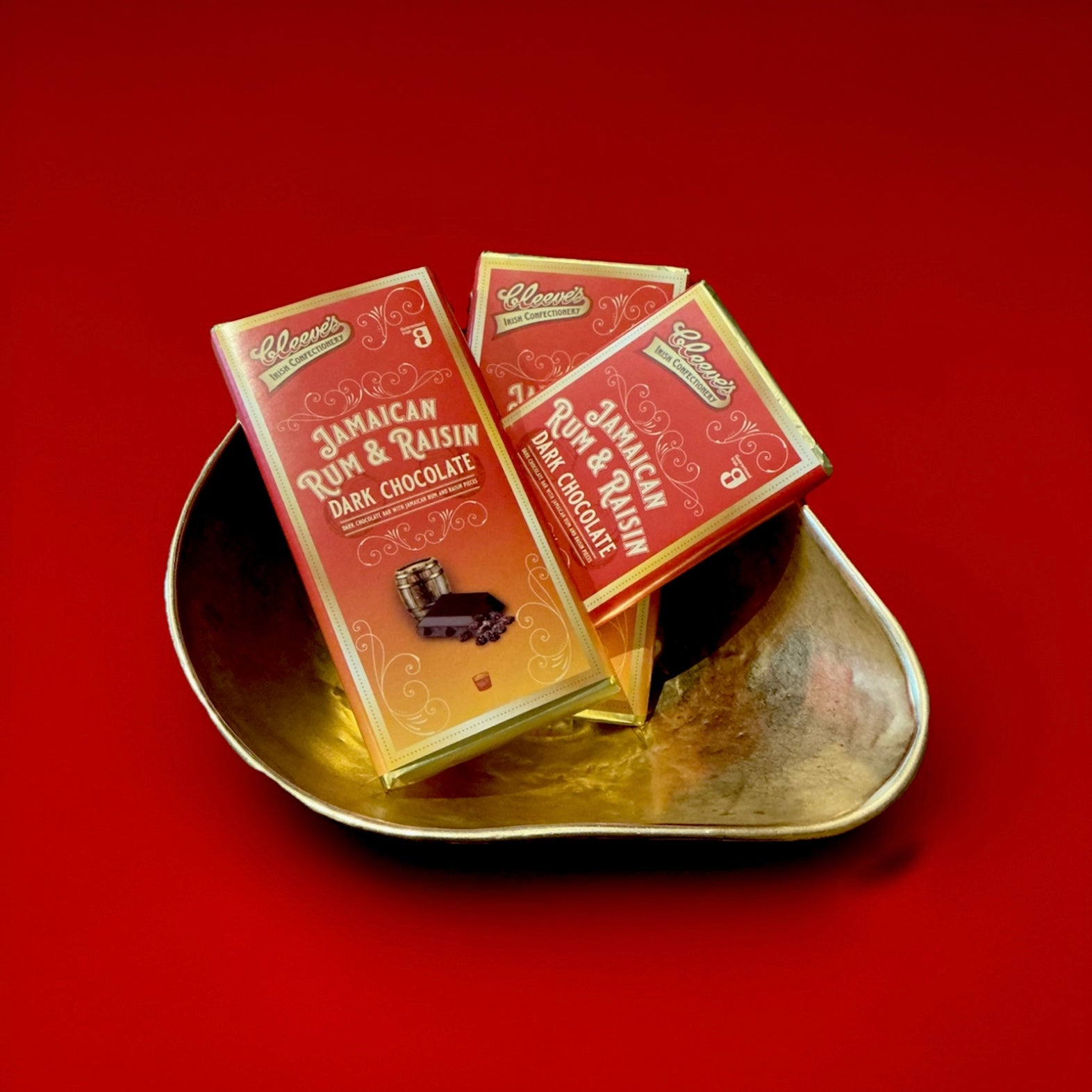 Old Jamaica rum and raisin dark chocolate in yellow orange and gold wrapper in a gold bowl on a red background 