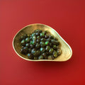 Traditional hard boiled dark green apple and peppermint sweets in a gold bowl with a red background 