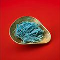 Blue raspberry flavoured sour laces in a gold bowl with a red background 