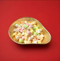 Multicoloured fruit flavoured bite sized pie of soft rock in a gold bowl on a red background 
