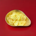 Large hard gum yellow pineapple slices coated in sugar in a gold bowl with a red background 